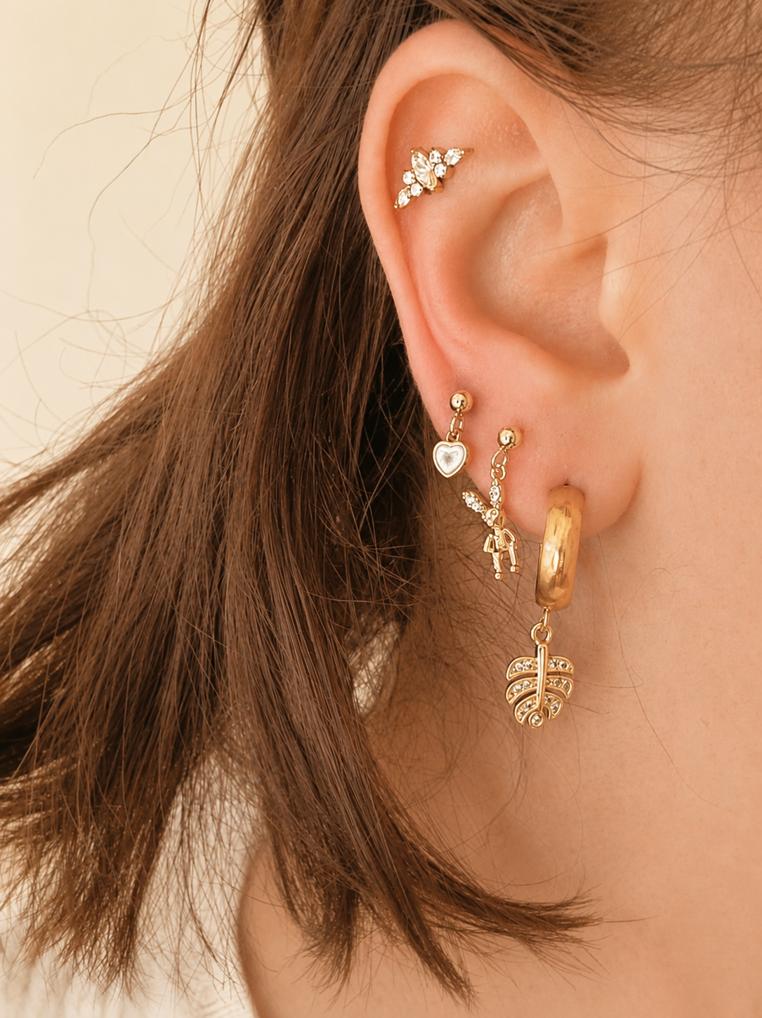 Buttermelle charm earrings worn on an ear