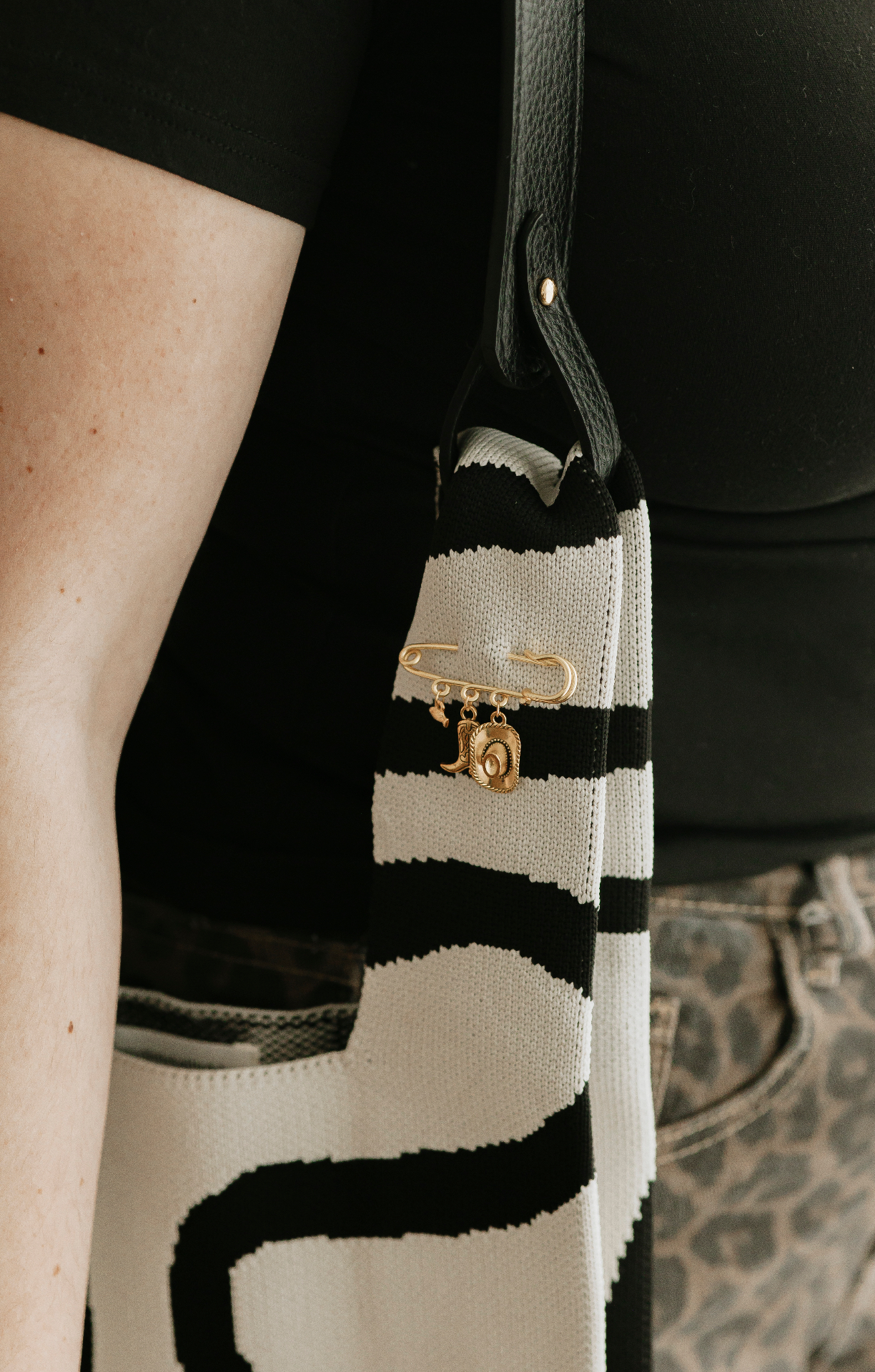 Buttermelle charm brooch pinned to a striped knit bag